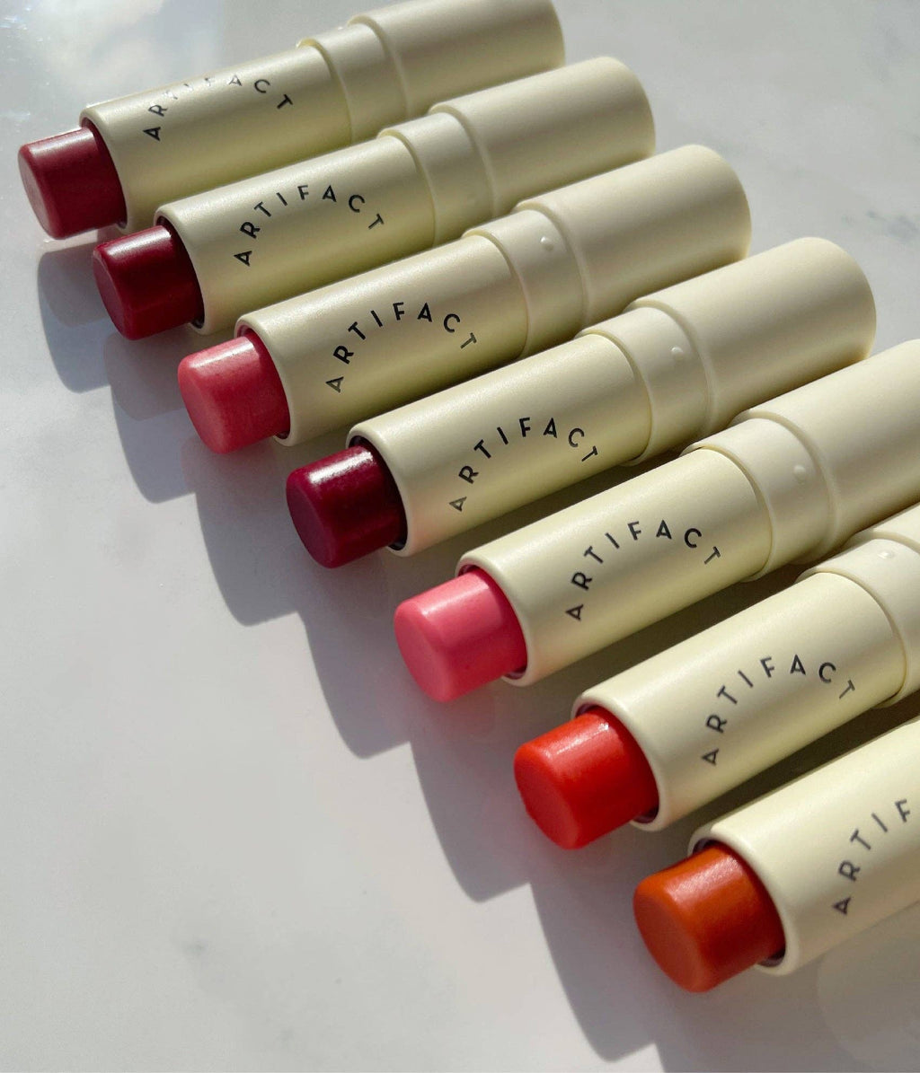 Swatches of sheer tinted lip balm shades including pink, coral red, rose, and cherry tones.