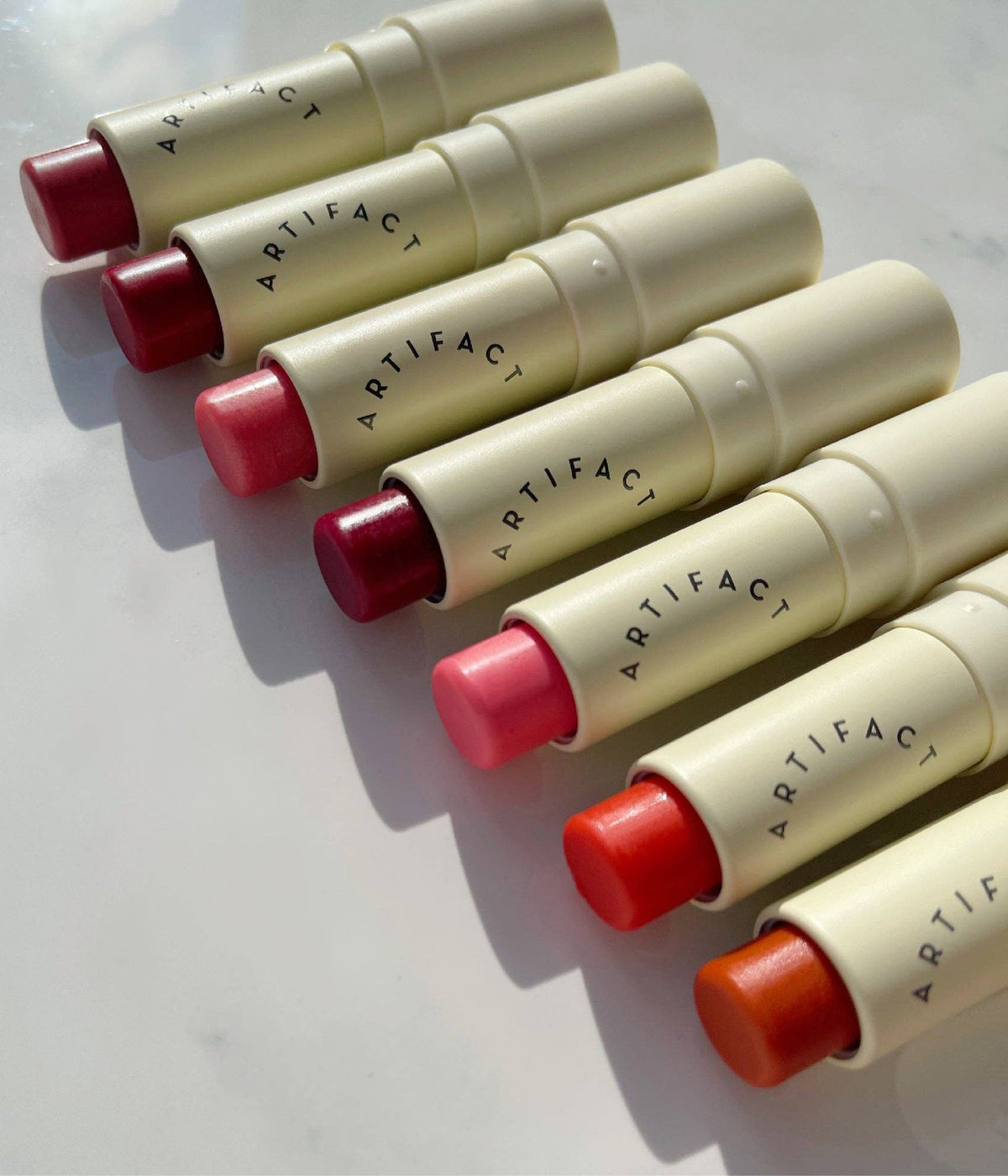 Swatches of sheer tinted lip balm shades including pink, coral red, rose, and cherry tones.